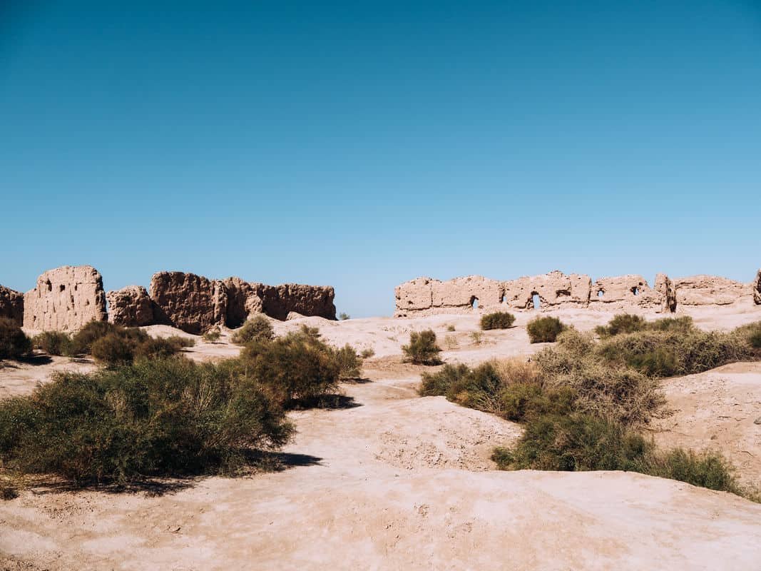 Ancient ruins on a dry, sandy landscape under a clear blue sky.