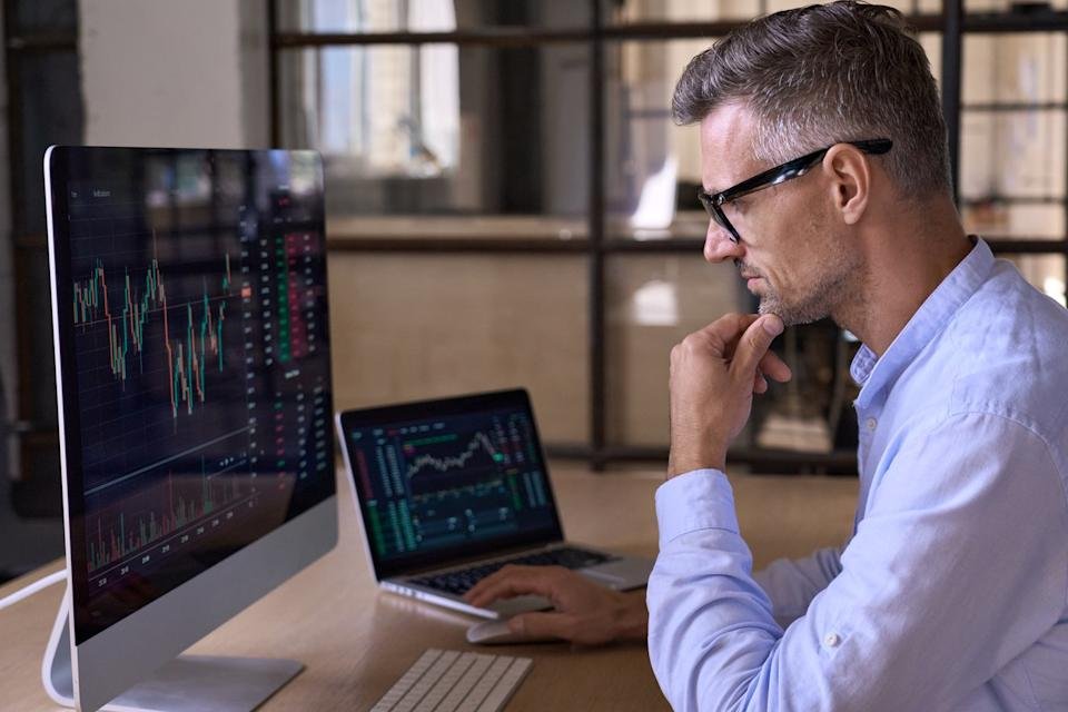 Man looking at financial charts on monitors.