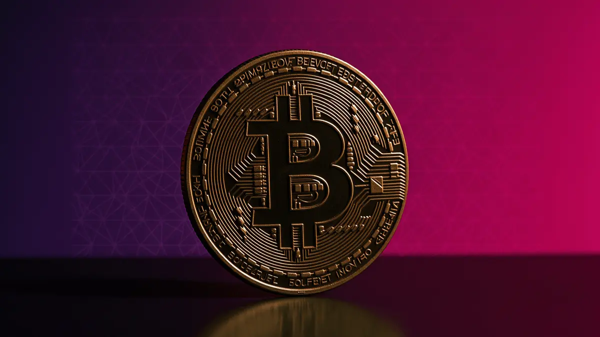 Bitcoin coin with dramatic studio lighting against purple-magenta gradient background